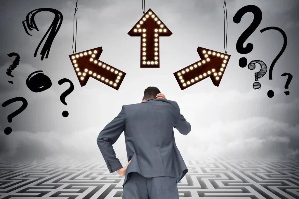 Homem de terno visto de costas, com a mão na cabeça, parado diante de três setas iluminadas apontando para direções diferentes