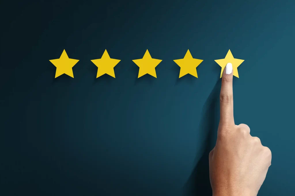 Mão tocando a quinta estrela em uma escala de avaliação, representando notas, reputação e confiança do consumidor em plataformas de venda online