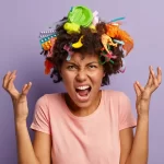 Mulher demonstrando frustração, com expressão de estresse e objetos acumulados na cabeça, simbolizando confusão, excesso de estímulos e queda de resultados nas vendas no pós-Carnaval