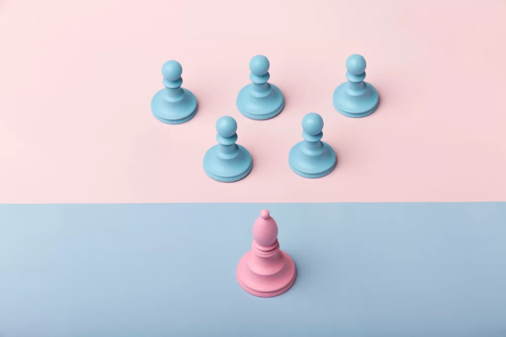 Peça de jogo no formato de peão rosa posicionada sozinha na parte inferior da imagem, enquanto cinco peões azuis estão agrupados na parte superior