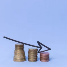 Pilhas de moedas de diferentes tamanhos com seta apontando para baixo, simbolizando redução de lucro