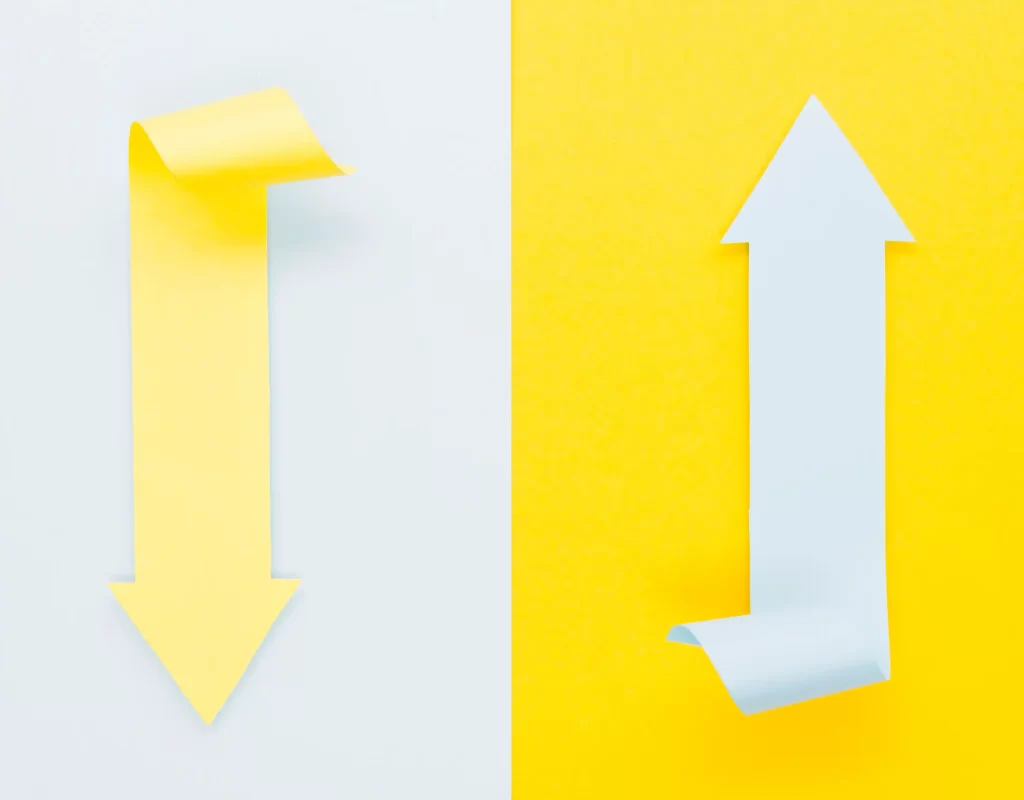 Seta amarela apontando para baixo ao lado de seta branca apontando para cima, representando aumento de visitas e queda na conversão