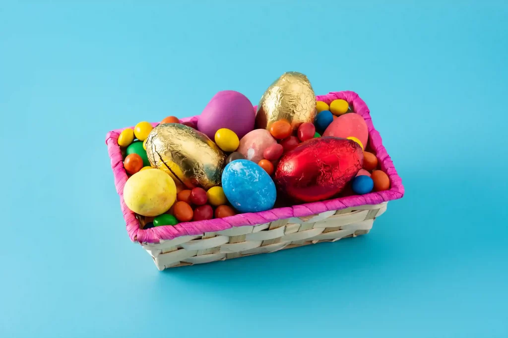 Cesta com ovos de Páscoa coloridos e chocolates representando aumento de demanda e necessidade de reforçar estoque para Páscoa