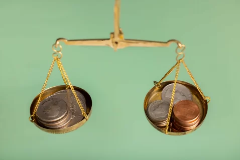 Balança com moedas em cada lado representando a decisão entre desconto e margem nas estratégias de preço no e-commerce