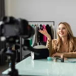 Influenciadora apresentando produtos durante transmissão de live commerce com câmera profissional em estúdio