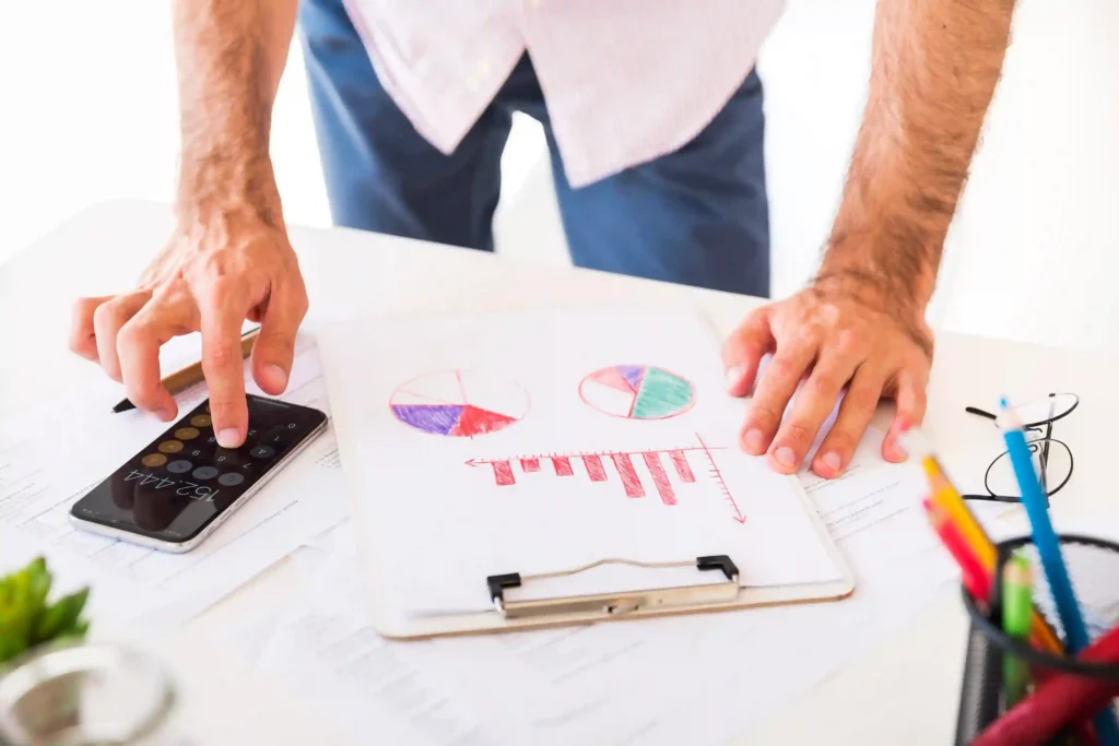 Pessoa analisando gráficos e usando calculadora para calcular margem de lucro no e-commerce