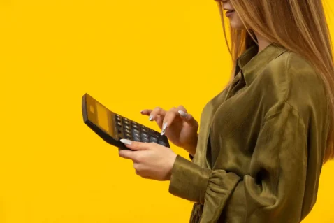 Mulher usando calculadora para calcular margem de lucro no e-commerce e definir preços de venda