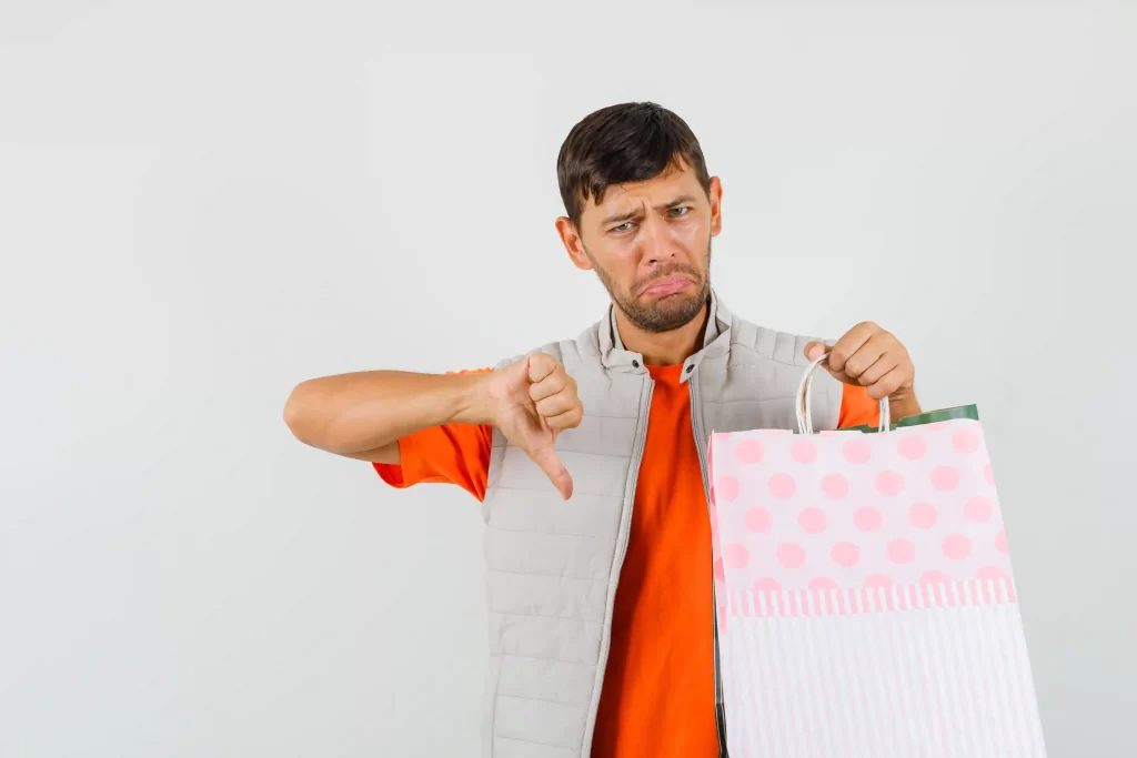 Homem segurando sacola de compras e fazendo sinal negativo com o polegar, representando erros internos que prejudicam o posicionamento no Mercado Livre