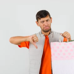 Homem segurando sacola de compras e fazendo sinal negativo com o polegar, representando erros internos que prejudicam o posicionamento no Mercado Livre