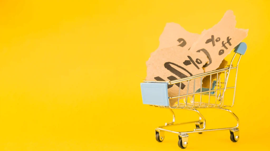 Carrinho de compras com papel escrito “buy” representando produtos baratos que incentivam compras recorrentes no e-commerce