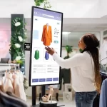 Consumidora interagindo com tela digital de produtos em loja representando anúncios e experiência de compra no retail media