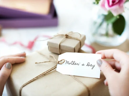 Mãos segurando etiqueta Mother's Day em presente embrulhado em papel kraft, representando a necessidade de ajustar o anúncio do Dia das Mães no Mercado Livre