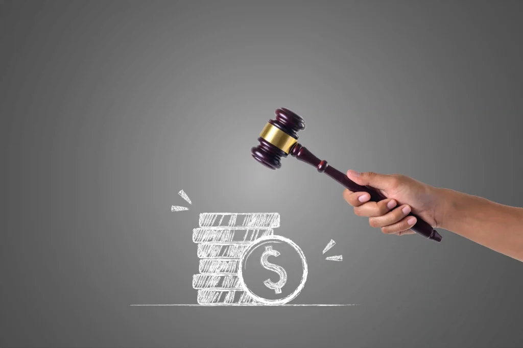 Mão segurando martelo de juiz sobre desenho de moedas e cifrão, representando decisão financeira e legalidade