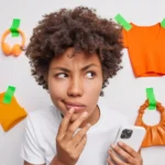 Mulher pensativa com smartphone rodeada de produtos fixados na parede, ilustrando o comportamento do consumidor pós-evento e a jornada de decisão de compra