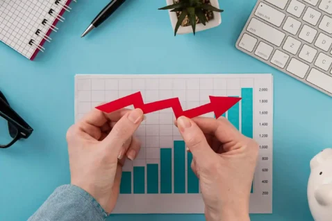 Mãos segurando seta vermelha irregular sobre gráfico de barras, ilustrando a desaceleração no crescimento do e-commerce e a nova fase do mercado