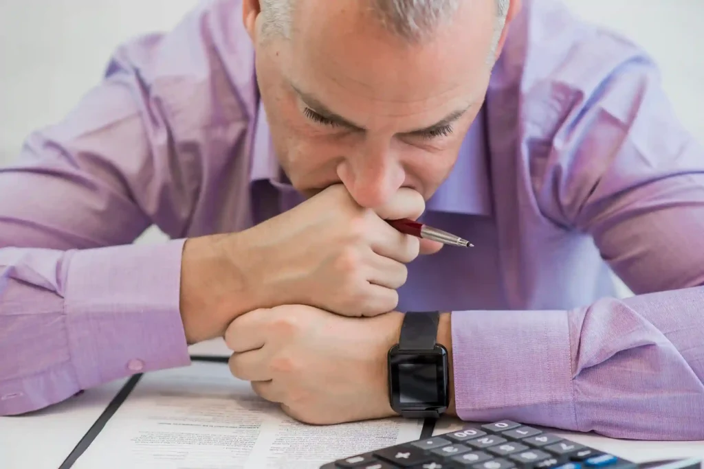 Homem preocupado analisando contas e calculadora, representando taxas invisíveis que reduzem a margem no e-commerce