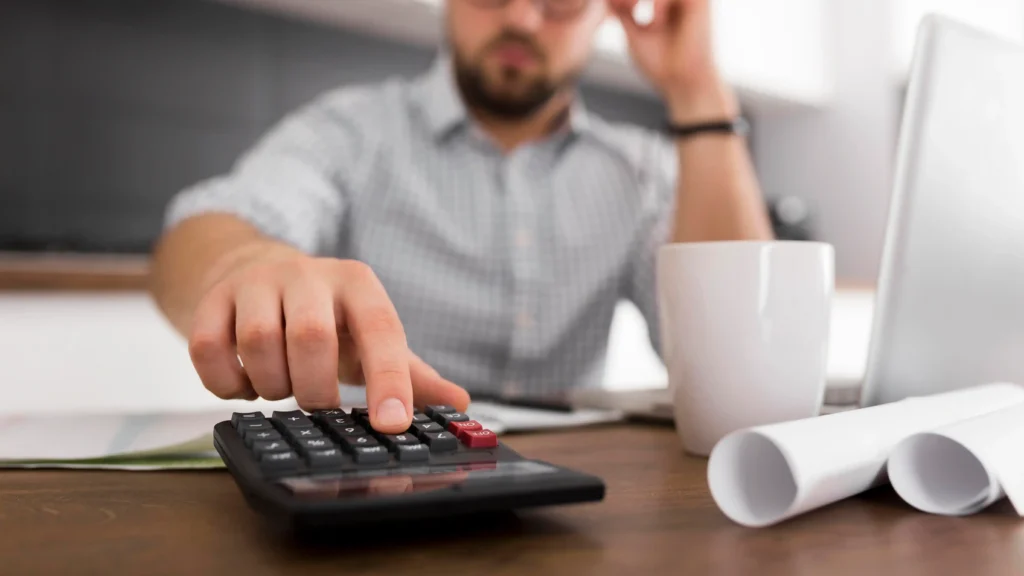 Pessoa usando calculadora ao analisar custos e impostos, representando erro na leitura de comissões e taxas no e-commerce