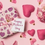 Presente embrulhado com papel estampado de corações roxos, laço rosa e cartão Happy Mother's Day rodeado de flores e corações de feltro sobre fundo rosa, ilustrando kit dia das mães para vender no Mercado Livre