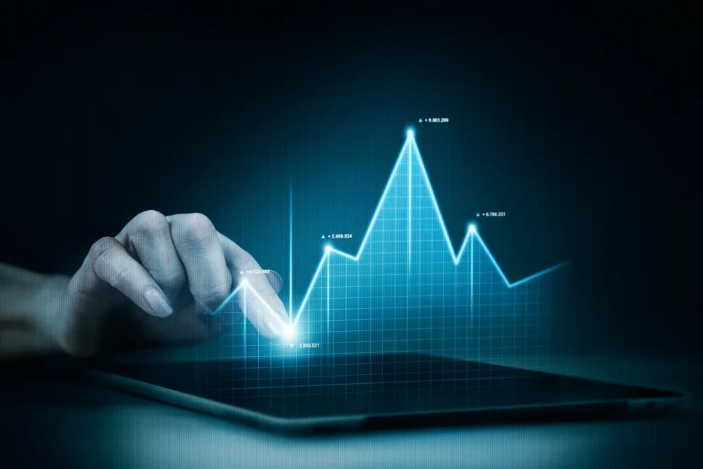 Mão interagindo com tablet exibindo gráfico digital azul com dados financeiros e tendências de crescimento