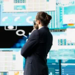 Homem de terno analisando múltiplos painéis de dados e gráficos em telas, ilustrando a análise estratégica para monitorar concorrentes no Mercado Livre