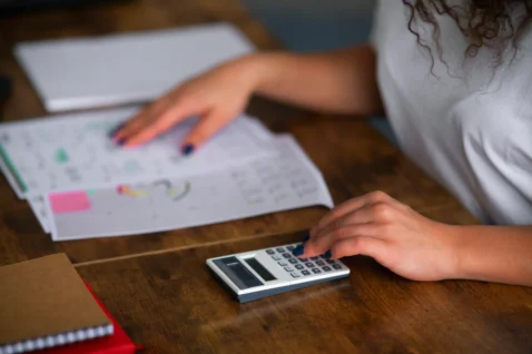 Pessoa usando calculadora com planilhas sobre a mesa, ilustrando a precificação no Mercado Livre para o Dia das Mães