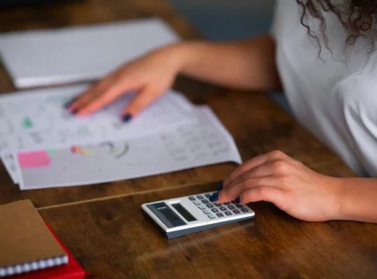 Pessoa usando calculadora com planilhas sobre a mesa, ilustrando a precificação no Mercado Livre para o Dia das Mães