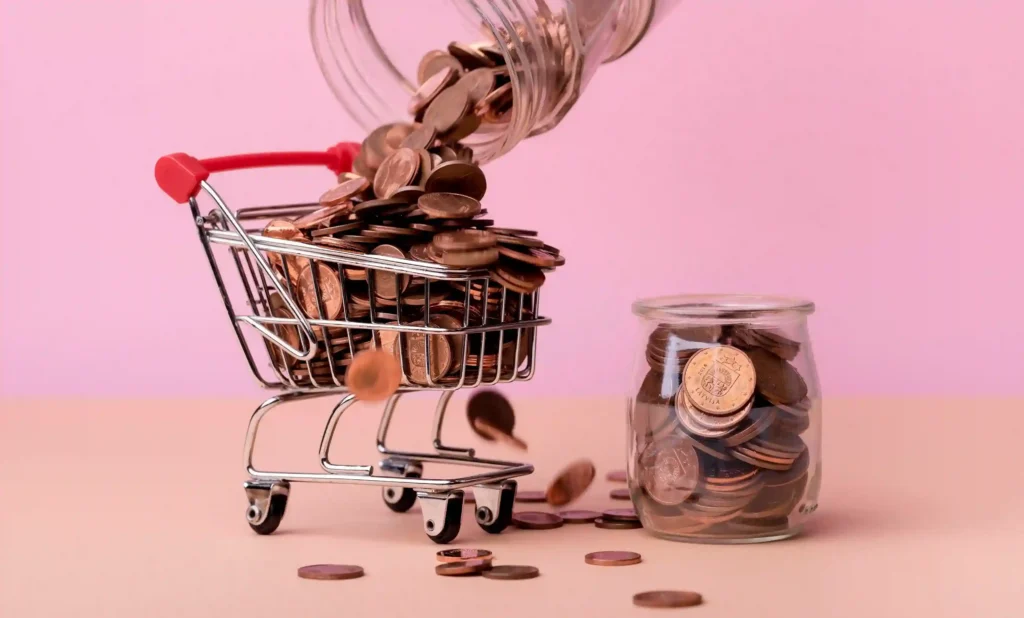 Carrinho de compras em miniatura cheio de moedas, com jarro despejando mais moedas, representando lucratividade no e-commerce