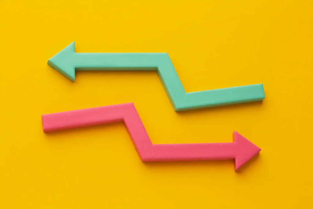 Duas setas em zigue-zague coloridas apontando em direções opostas sobre fundo amarelo, simbolizando contraste entre margem e volume