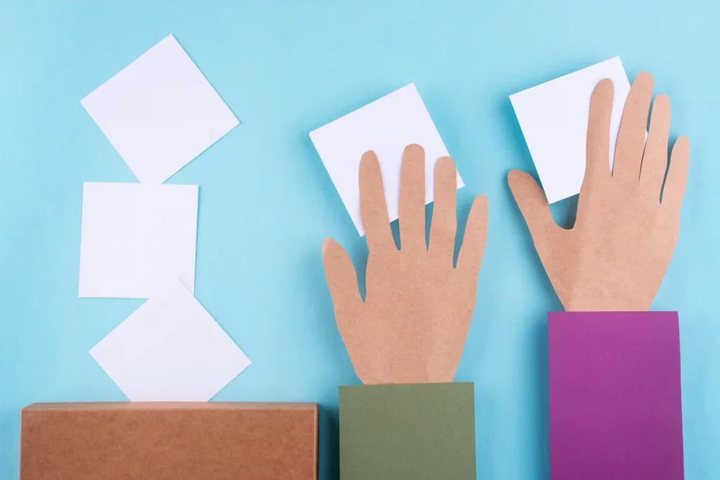 Mãos de papel recortado trocando cartões brancos sobre fundo azul, ilustrando o mercado de trocas de figurinhas da Copa 2026 como oportunidade para sellers