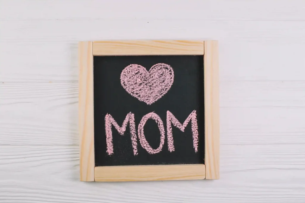 Quadro negro com coração e palavra MOM escritos em giz rosa, representando o encerramento do Dia das Mães e o momento de análise pós-data no Mercado Livre