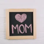 Quadro negro com coração e palavra MOM escritos em giz rosa, representando o encerramento do Dia das Mães e o momento de análise pós-data no Mercado Livre
