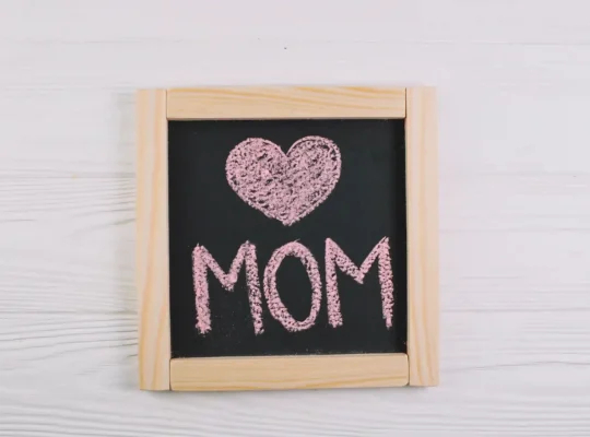 Quadro negro com coração e palavra MOM escritos em giz rosa, representando o encerramento do Dia das Mães e o momento de análise pós-data no Mercado Livre