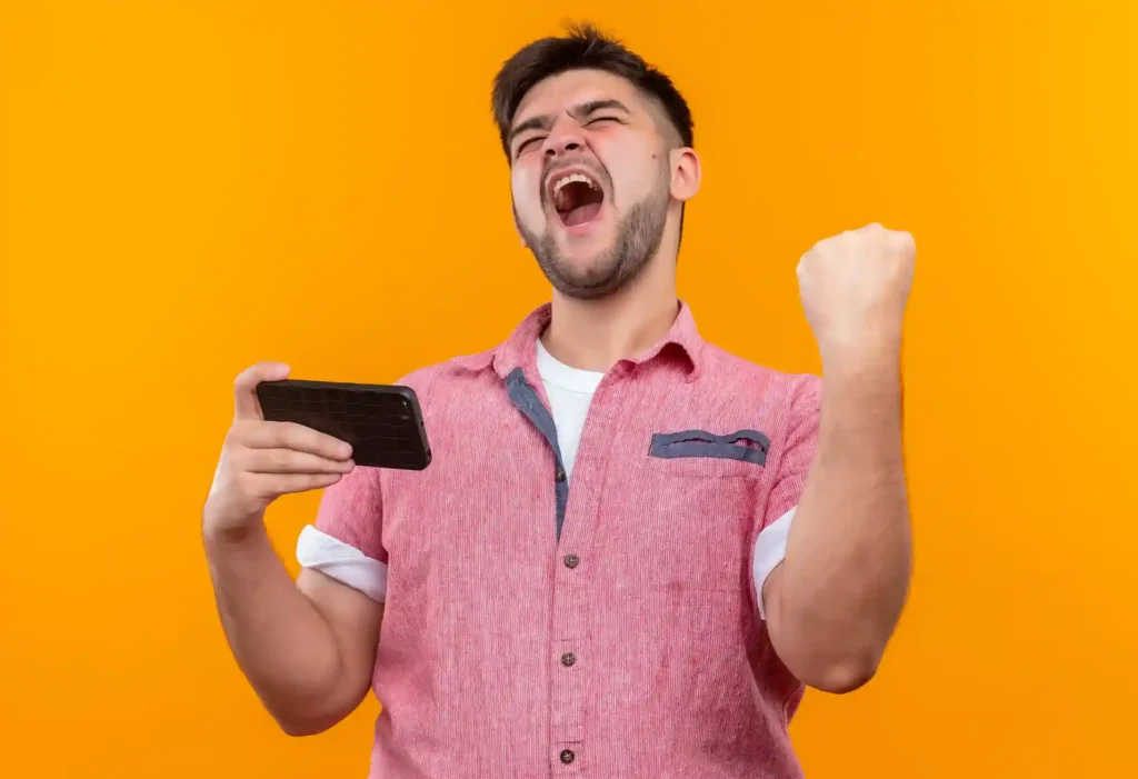 Homem empolgado comemorando com smartphone na mão, representando o comportamento de compras pelo celular durante a Copa 2026 e a oportunidade de vender pelo mobile no Mercado Livre
