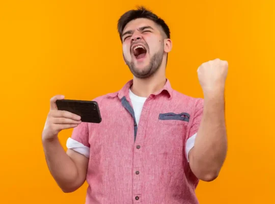 Homem empolgado comemorando com smartphone na mão, representando o comportamento de compras pelo celular durante a Copa 2026 e a oportunidade de vender pelo mobile no Mercado Livre
