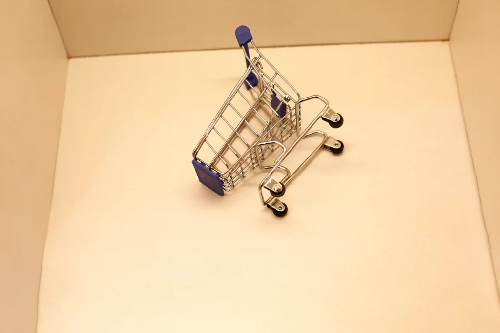 Carrinho de compras tombado e vazio sobre superfície clara, ilustrando a oportunidade de ganhar posição no Mercado Livre quando um concorrente sai do nicho