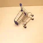 Carrinho de compras tombado e vazio sobre superfície clara, ilustrando a oportunidade de ganhar posição no Mercado Livre quando um concorrente sai do nicho