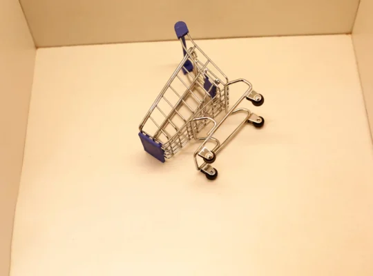 Carrinho de compras tombado e vazio sobre superfície clara, ilustrando a oportunidade de ganhar posição no Mercado Livre quando um concorrente sai do nicho
