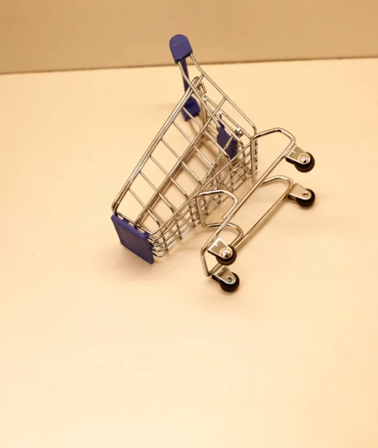 Carrinho de compras tombado e vazio sobre superfície clara, ilustrando a oportunidade de ganhar posição no Mercado Livre quando um concorrente sai do nicho