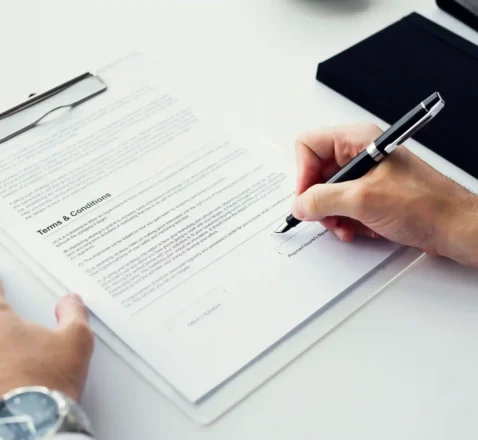 Pessoa assinando documento de termos e condições em prancheta, representando o contrato de adesão do Mercado Livre que todo vendedor aceita ao criar sua conta