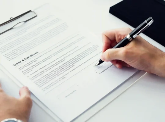 Pessoa assinando documento de termos e condições em prancheta, representando o contrato de adesão do Mercado Livre que todo vendedor aceita ao criar sua conta