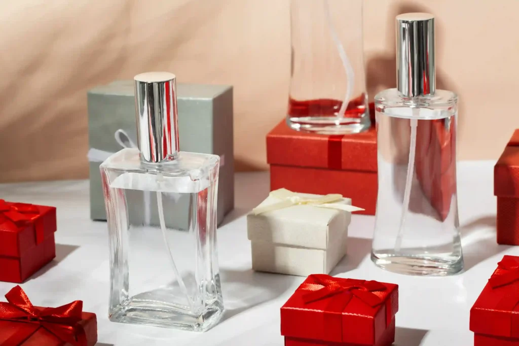 Frascos de perfume e caixas de presente vermelhas e brancas sobre mesa, representando produtos do Dia dos Namorados 2026 com sinal de aquecimento no Mercado Livre