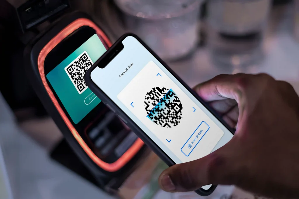 Pessoa aproximando um celular com QR Code de uma máquina de pagamento para realizar pagamento via Pix