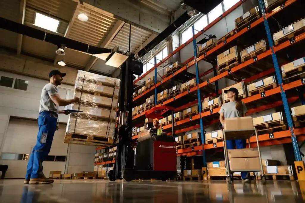 Equipe trabalhando em galpão de fulfillment com empilhadeira e prateleiras de caixas, representando a logística para e-commerce em crescimento e as alternativas ao envio terceirizado