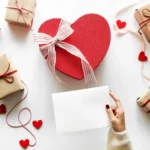 Flatlay com caixa coração vermelha, presentes embrulhados e corações decorativos, ilustrando kits do Dia dos Namorados 2026 para vender no e-commerce