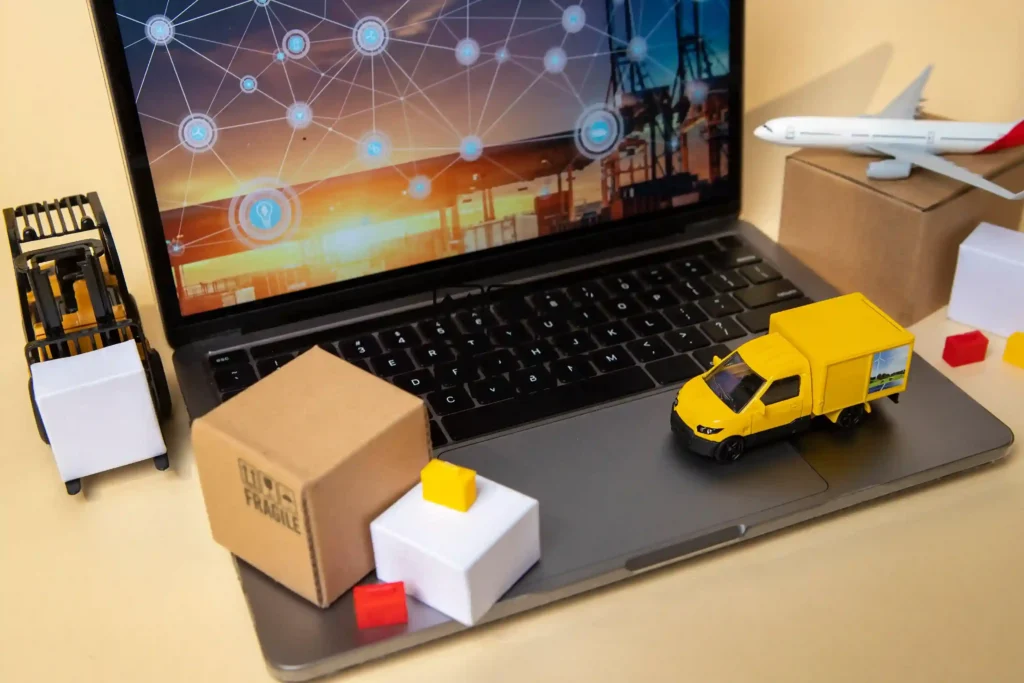 Miniatura de caminhão de entrega e caixa fragile sobre notebook com rede logística na tela, representando a entrega rápida no marketplace como fator de conversão no e-commerce