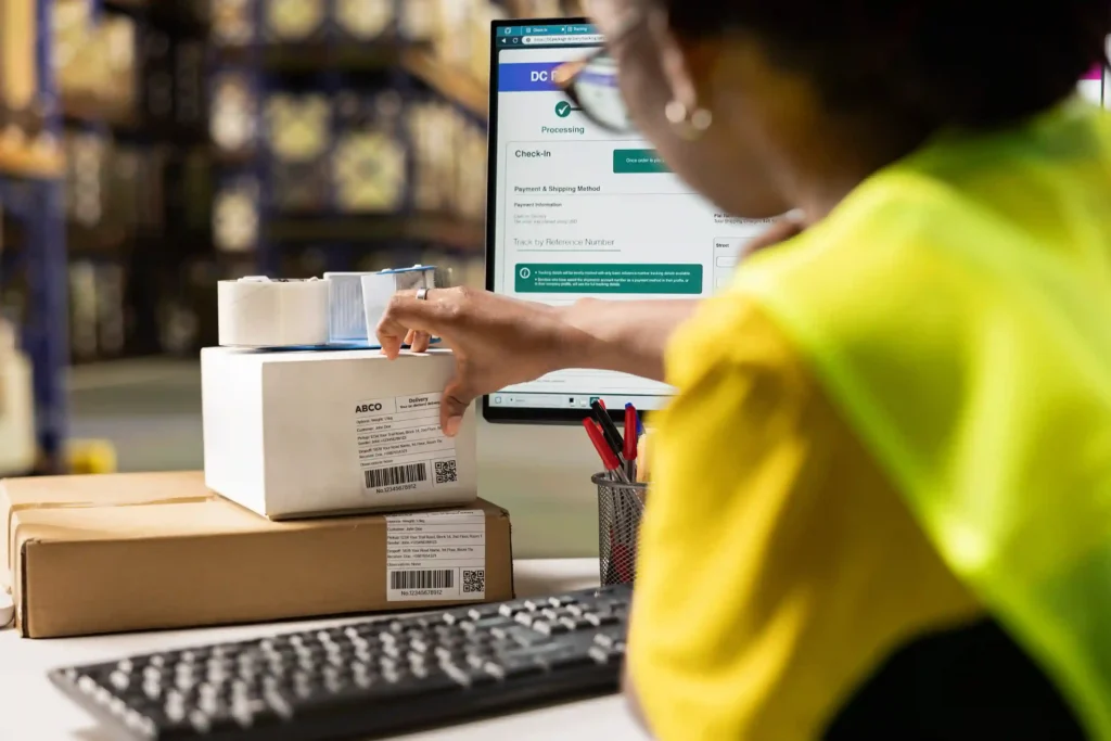 Operadora de logística preparando pacotes com sistema de rastreamento na tela, representando a estratégia de logística no e-commerce em 2026 para sellers no Mercado Livre