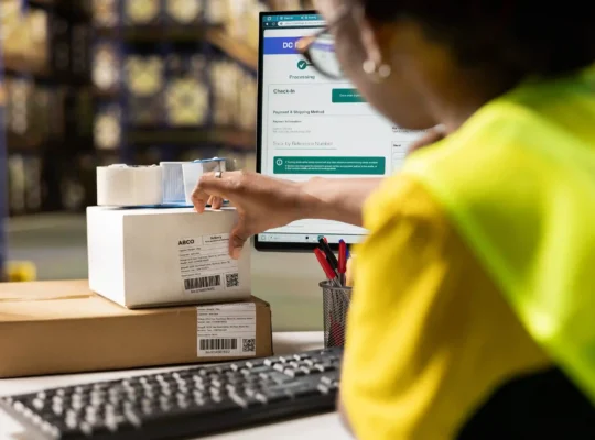 Operadora de logística preparando pacotes com sistema de rastreamento na tela, representando a estratégia de logística no e-commerce em 2026 para sellers no Mercado Livre