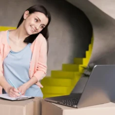 Empreendedora anotando em prancheta ao lado de caixas e notebook, ilustrando como negociar com fornecedor no e-commerce e melhorar a margem sem aumentar volume