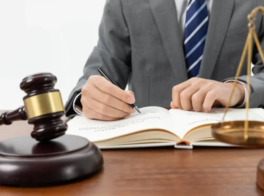 Advogado escrevendo em livro jurídico com martelo e balança da justiça sobre mesa, ilustrando como a LC 214 transforma o marketplace em fiscal do vendedor na reforma tributária
