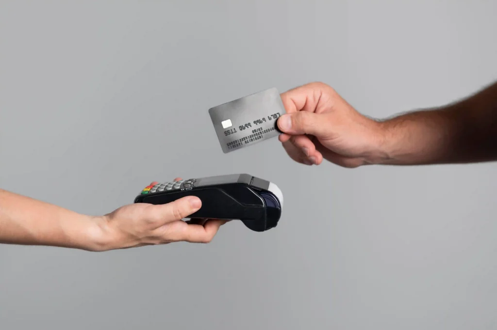 Mão aproximando cartão de crédito de maquininha de pagamento, ilustrando o parcelamento sem juros no Mercado Livre como estratégia para vender mais